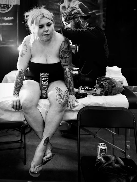 Bored Blonde on Table Getting Tattoo with Pringles Can