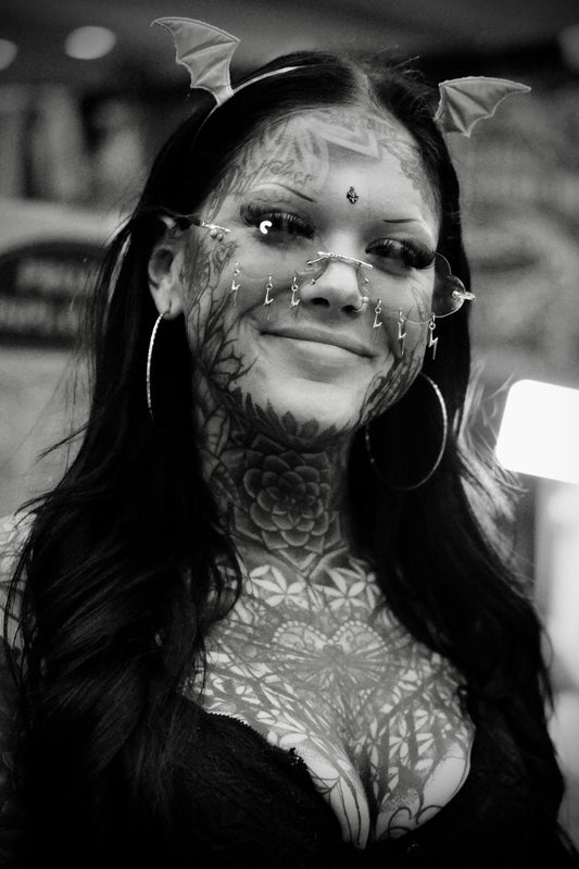 Smiling Woman with Full Chest Tattoo and Hook Glasses